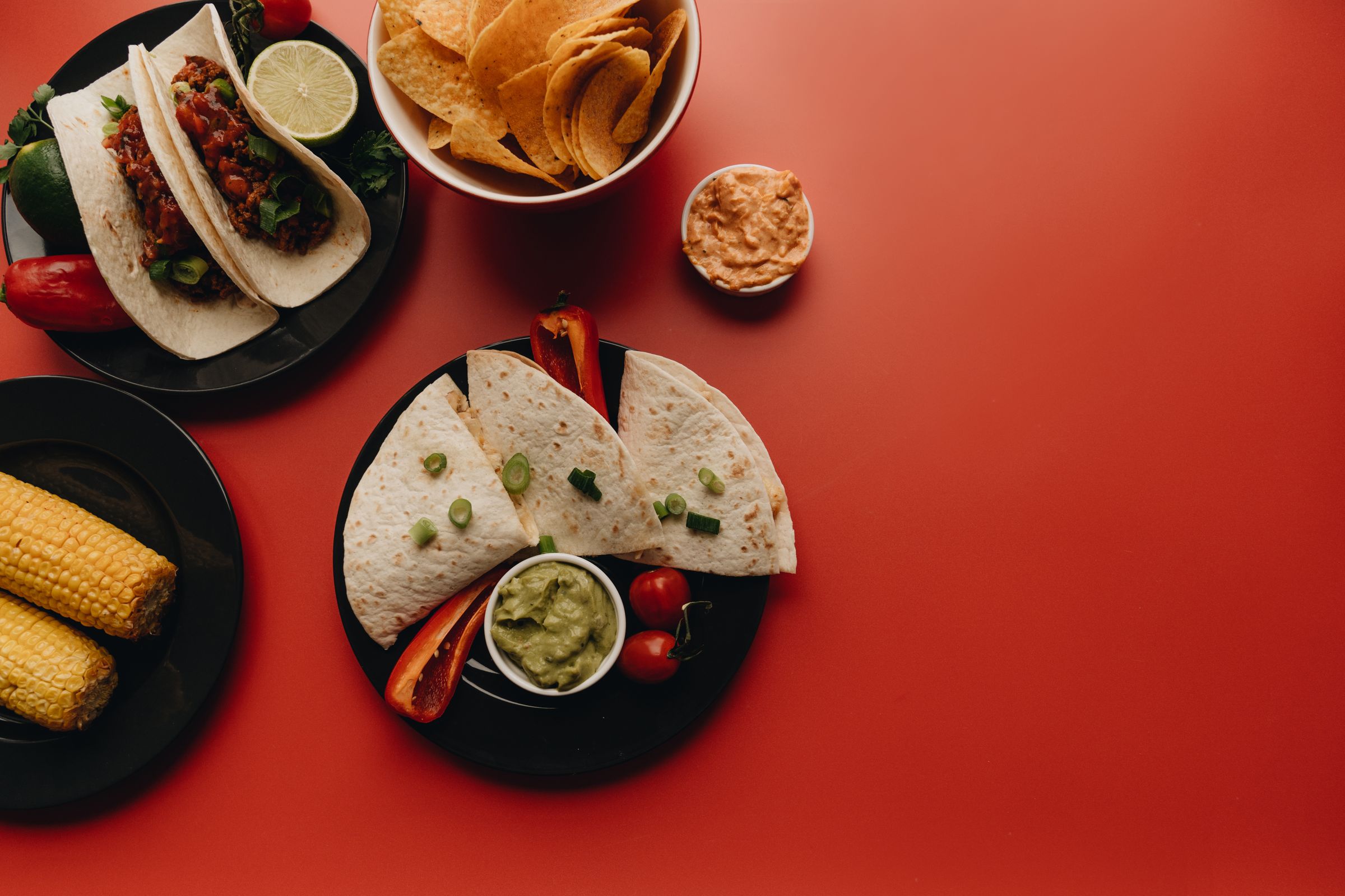An overhead spread of tacos, quesadillas, tortilla chips, corn and fresh salsa